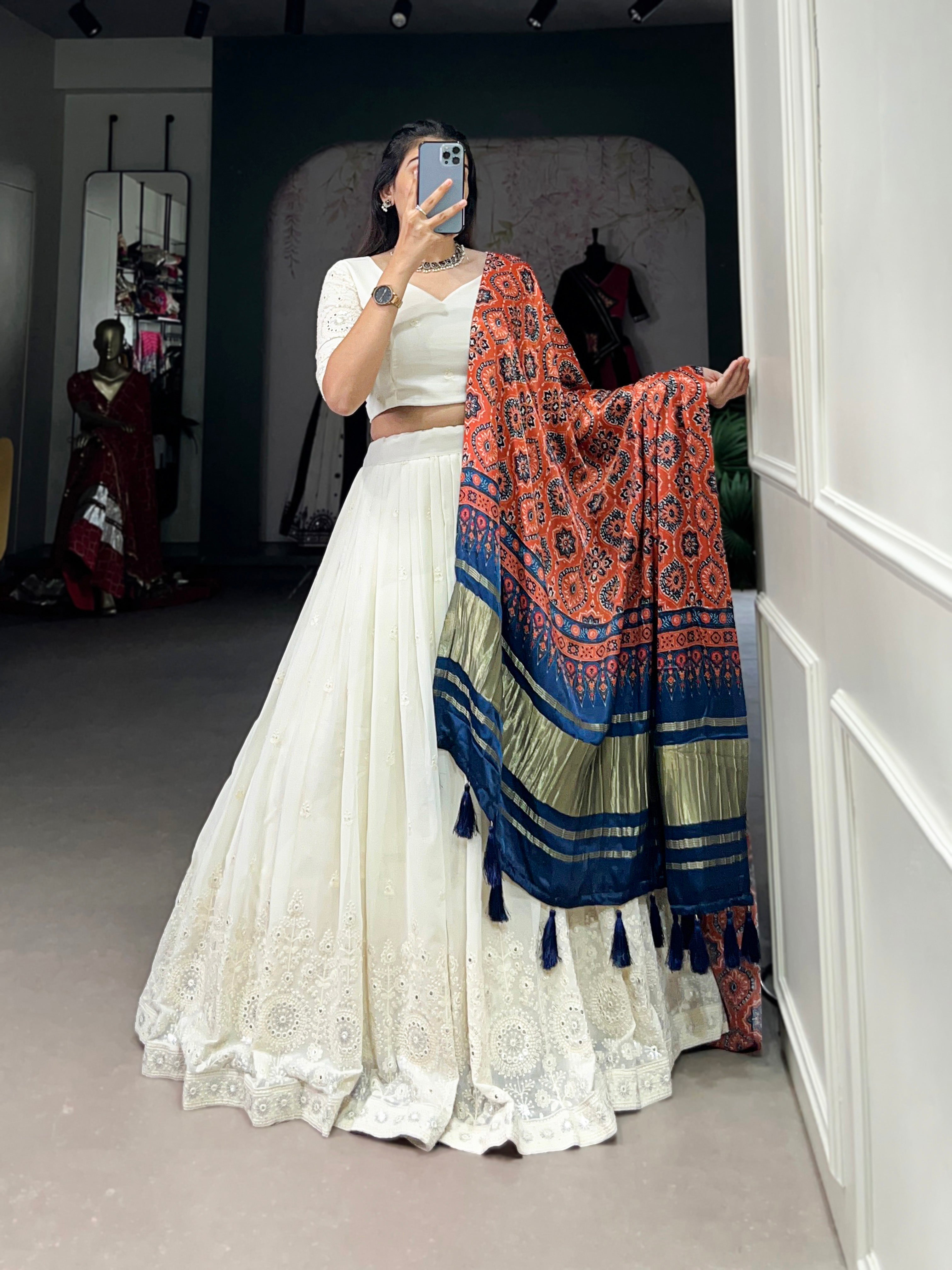 A chic white lehenga brought to life by a stunning rust and blue dupatta.