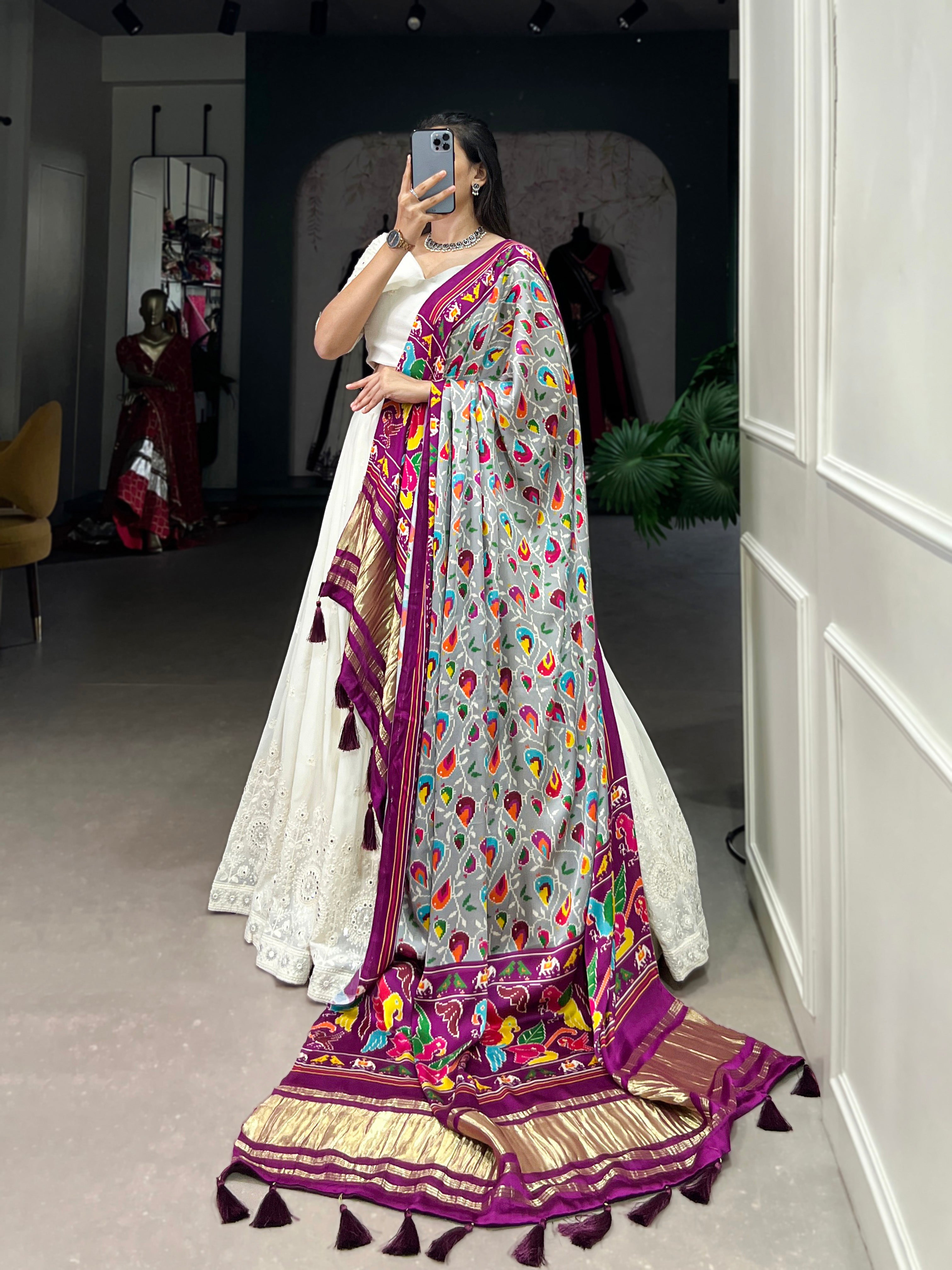 A chic white lehenga brought to life by a stunning rust and blue dupatta.