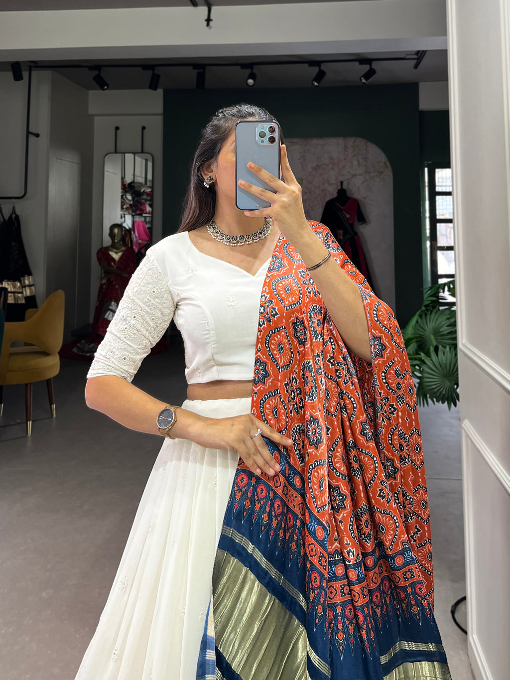A chic white lehenga brought to life by a stunning rust and blue dupatta.